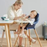 Chaise haute repas bébé évolutive en bleu foncé, avec harnais de sécurité et plateau amovible, idéale pour les repas des enfants.